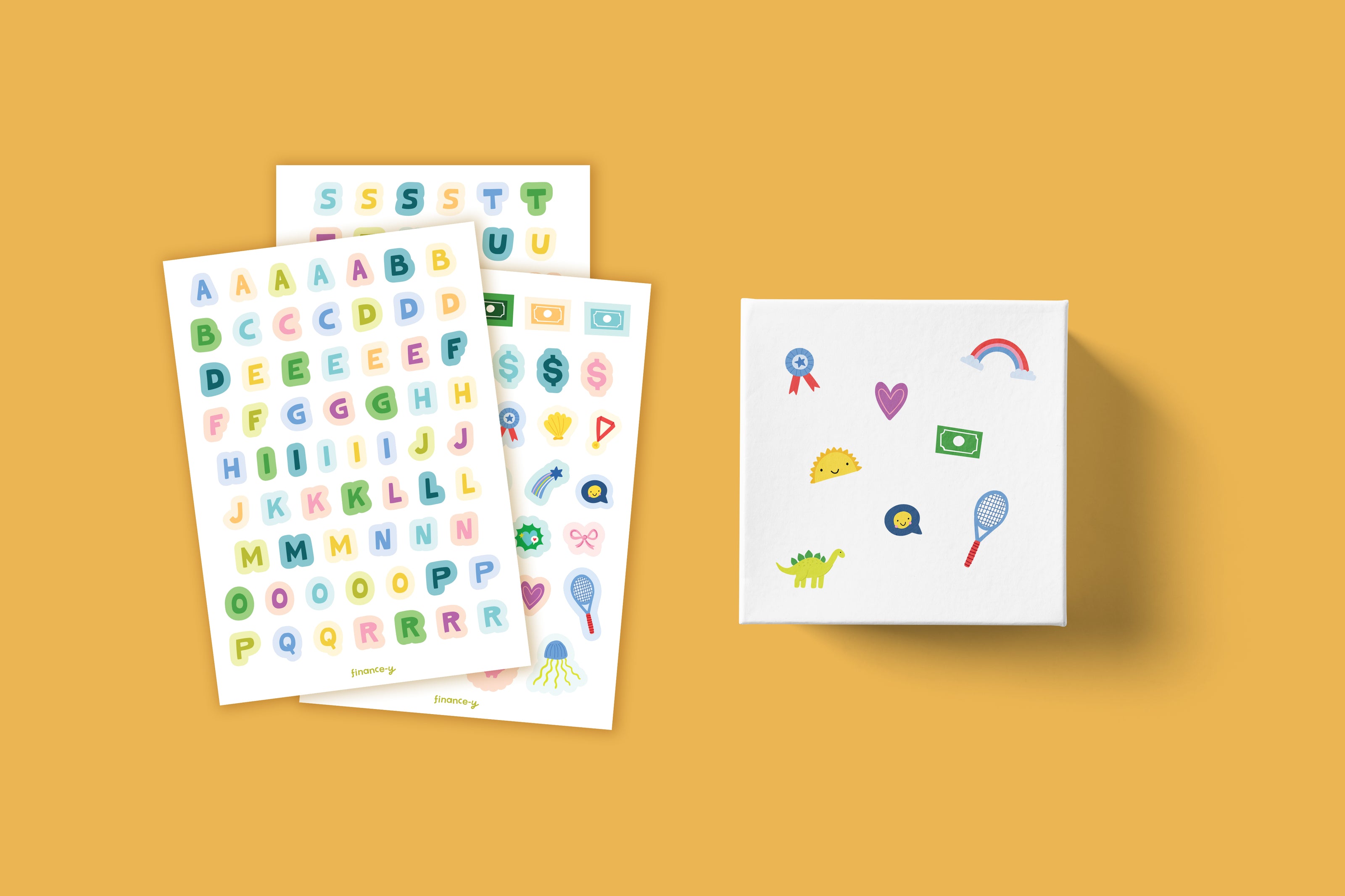 Finance-y Box 3 savings box and alphabet sticker sheets — colorful letter stickers for kids to personalize a white savings box decorated with fun icons including Morris the Crocodile, a rainbow, dollar bill, and taco, a hands-on money activity for ages 6–8